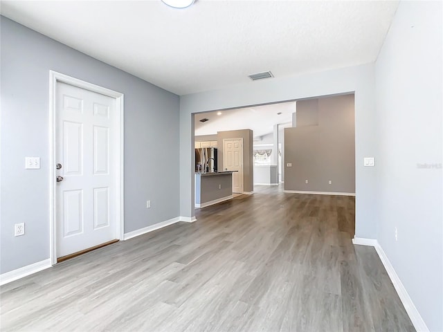 unfurnished living room with light wood-style floors, baseboards, and visible vents