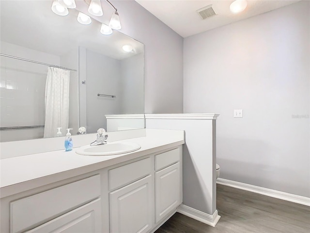 bathroom with baseboards, visible vents, a shower with curtain, wood finished floors, and vanity