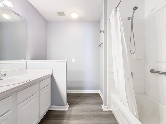 bathroom with wood finished floors, visible vents, vanity, baseboards, and shower / bath combo with shower curtain