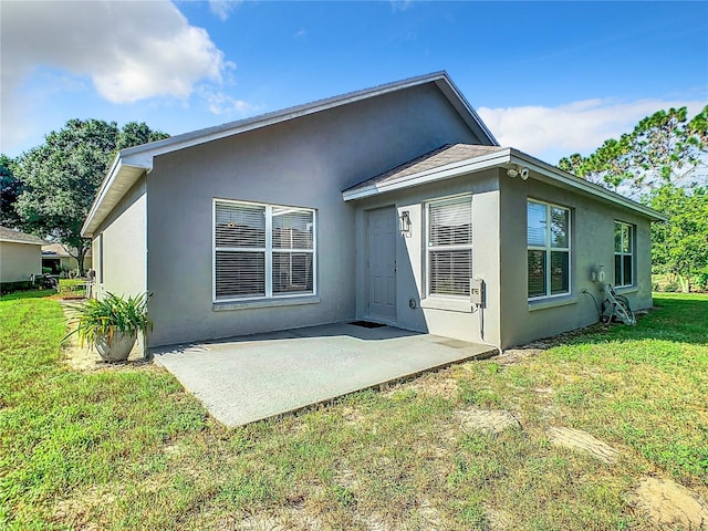 rear view of property with a patio, a yard, and stucco siding