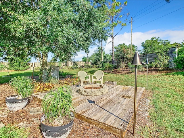 deck featuring a fire pit, a lawn, and fence