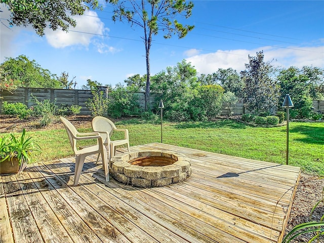 wooden deck featuring a yard, an outdoor fire pit, and a fenced backyard