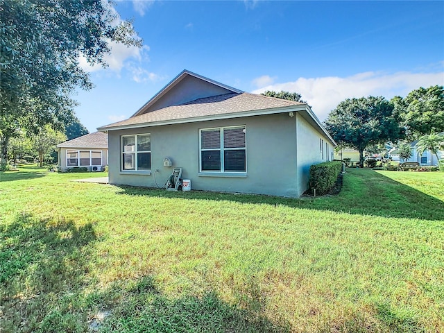 back of property featuring a yard, roof with shingles, and stucco siding