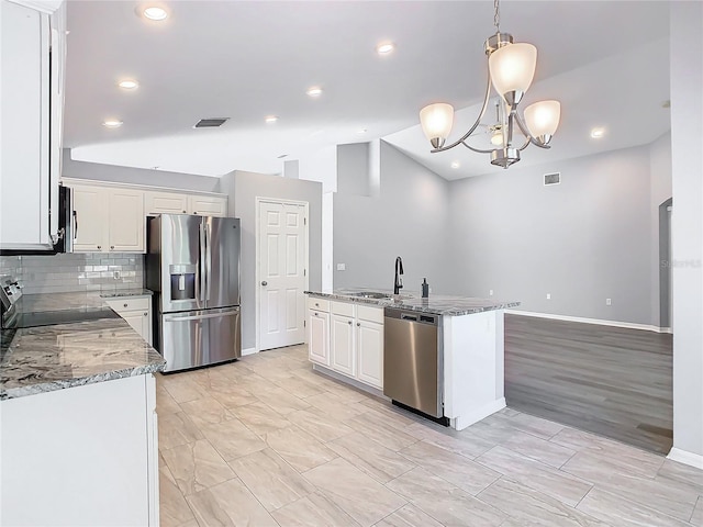 kitchen with stainless steel appliances, visible vents, hanging light fixtures, white cabinets, and an island with sink