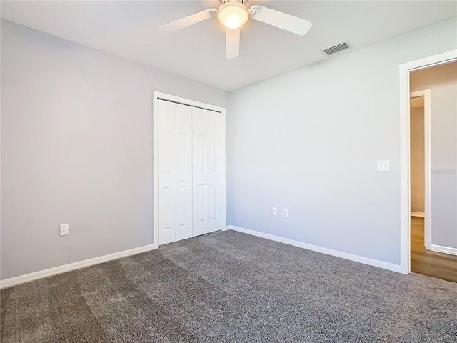 unfurnished bedroom with ceiling fan, visible vents, baseboards, a closet, and dark carpet