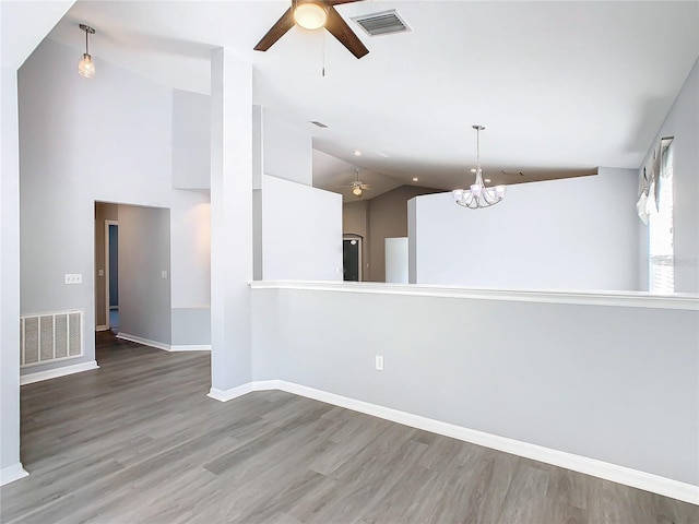 unfurnished room with ceiling fan with notable chandelier, wood finished floors, baseboards, and visible vents