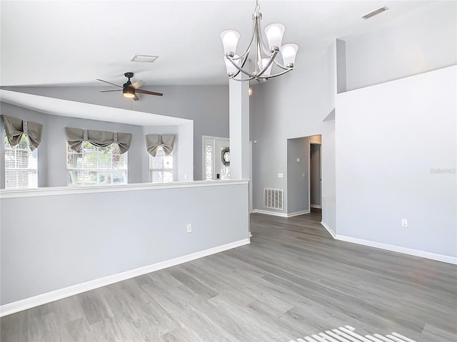 unfurnished room with visible vents, ceiling fan with notable chandelier, wood finished floors, and lofted ceiling