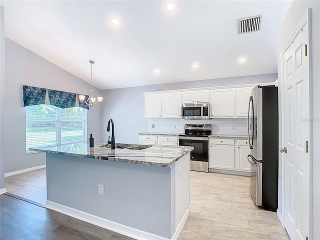 kitchen with visible vents, a sink, vaulted ceiling, light stone countertops, and stainless steel appliances