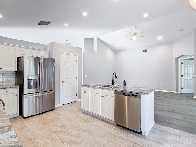 kitchen with vaulted ceiling, ceiling fan, stainless steel appliances, arched walkways, and a sink