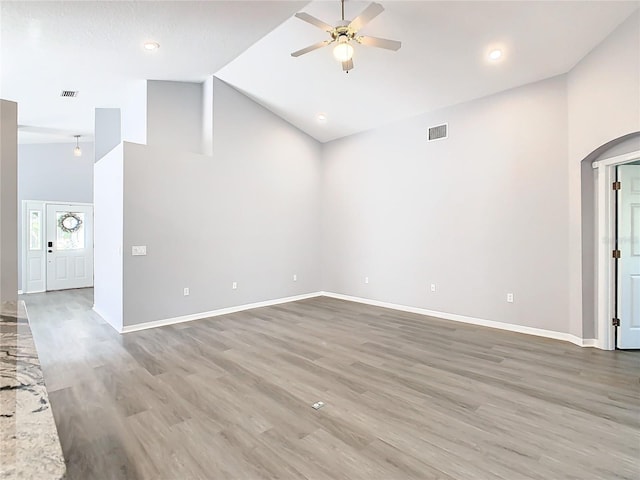 unfurnished living room featuring light wood finished floors, high vaulted ceiling, baseboards, and a ceiling fan
