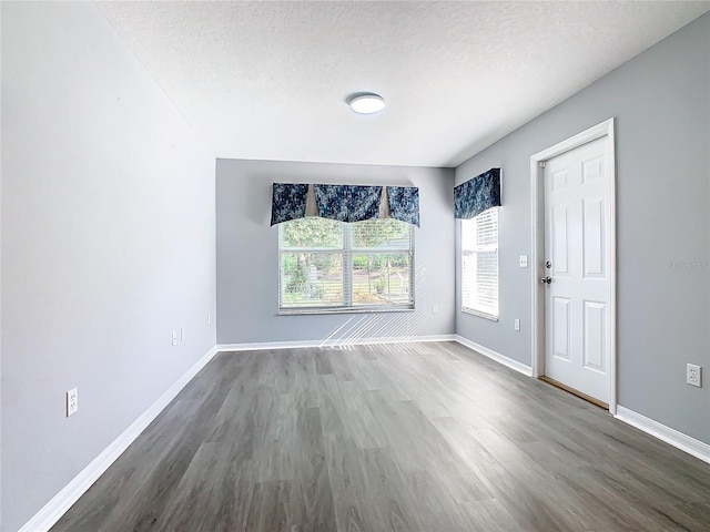 interior space with dark wood-style flooring, baseboards, and a textured ceiling