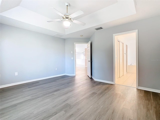 unfurnished bedroom featuring baseboards, a ceiling fan, connected bathroom, visible vents, and wood finished floors