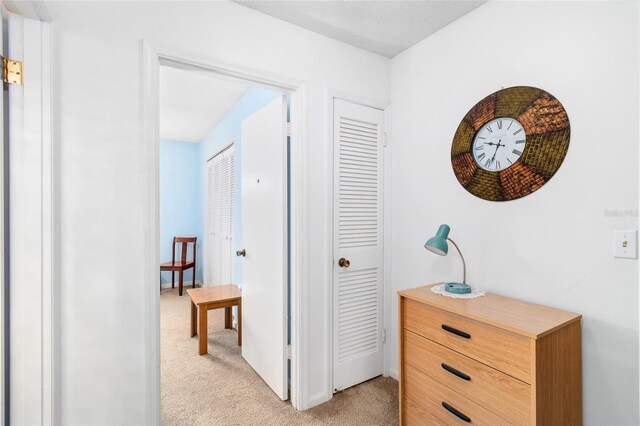 hallway featuring light colored carpet