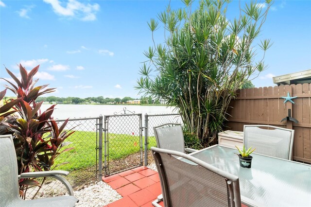 view of patio / terrace with a water view, fence, and a gate