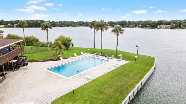 community pool featuring a water view, a yard, fence, and a patio