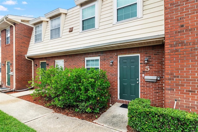 doorway to property featuring brick siding