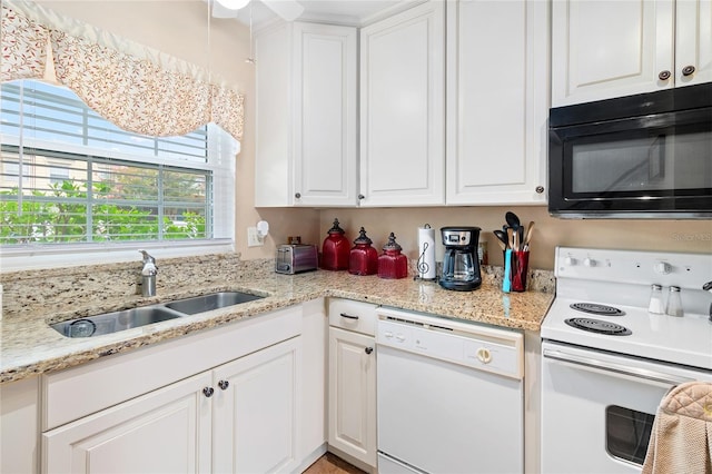 kitchen with white appliances, white cabinets, a sink, and light stone countertops