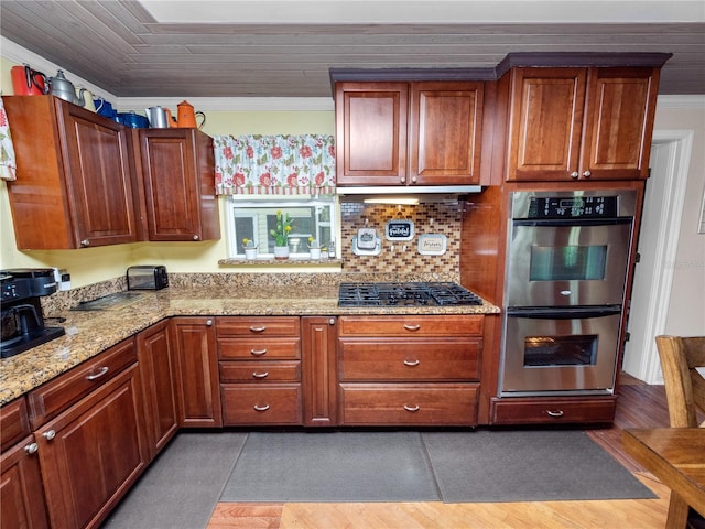 kitchen with ornamental molding, light stone counters, backsplash, and stainless steel appliances