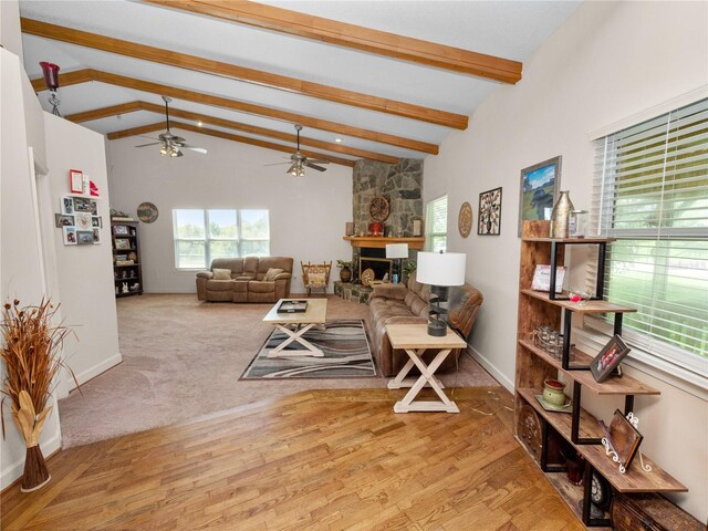 living room with light carpet, a fireplace, ceiling fan, and vaulted ceiling with beams