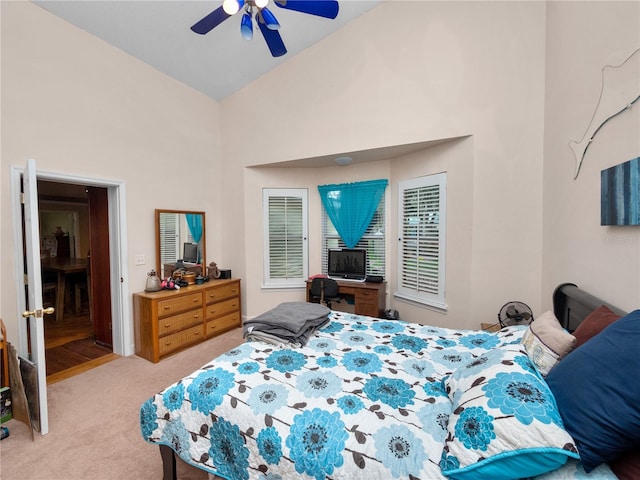 carpeted bedroom with ceiling fan and high vaulted ceiling