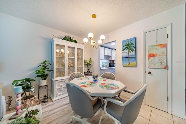 dining space featuring light tile patterned flooring, a notable chandelier, and a textured ceiling