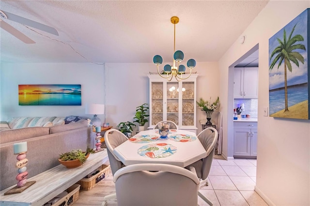 tiled dining area featuring ceiling fan with notable chandelier and a textured ceiling