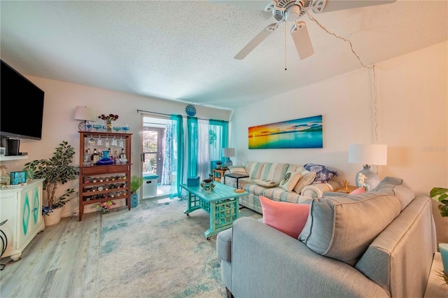 living room featuring ceiling fan, light hardwood / wood-style floors, and a textured ceiling