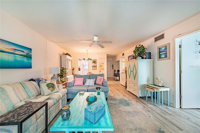 living room featuring a textured ceiling, ceiling fan, and light hardwood / wood-style flooring