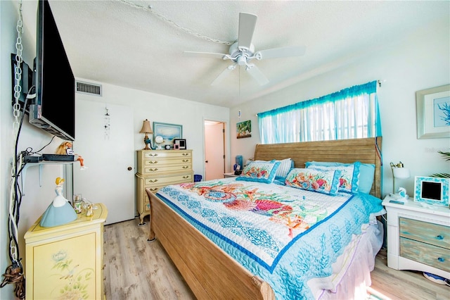 bedroom with ceiling fan, a textured ceiling, and light hardwood / wood-style floors