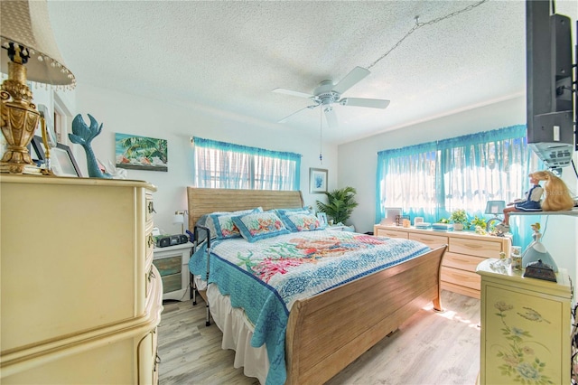 bedroom with a textured ceiling, multiple windows, and light hardwood / wood-style flooring