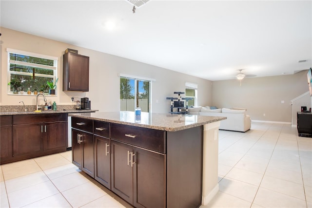 kitchen featuring sink, a kitchen island, plenty of natural light, and light stone countertops