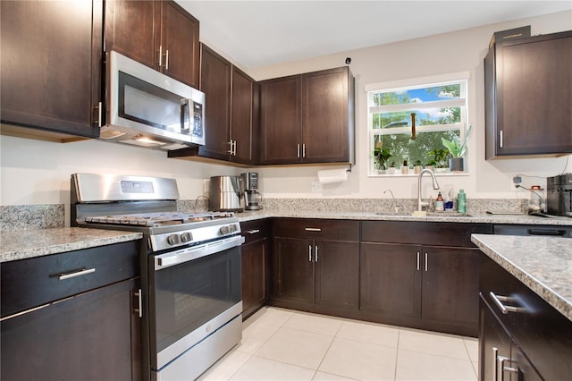 kitchen with dark brown cabinets, light tile patterned floors, stainless steel appliances, and sink