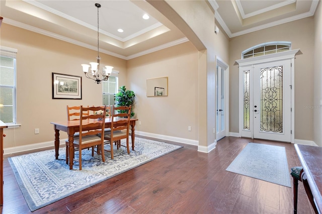 foyer entrance with a raised ceiling, dark hardwood / wood-style floors, an inviting chandelier, and crown molding