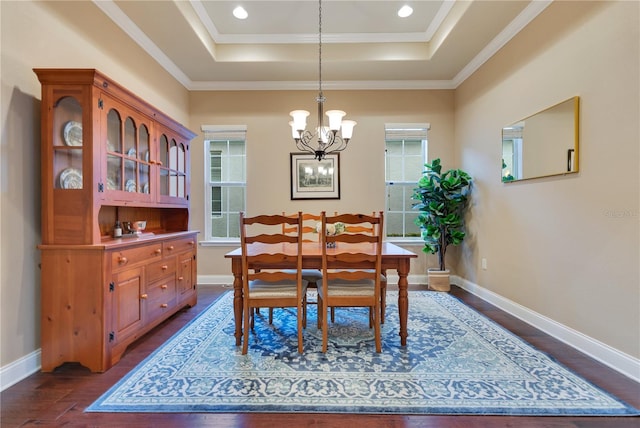 dining area with a raised ceiling, a wealth of natural light, dark hardwood / wood-style flooring, and a chandelier