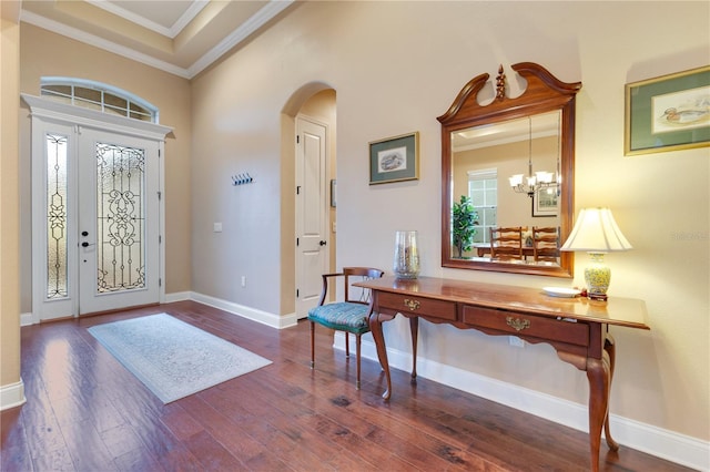 foyer entrance featuring dark hardwood / wood-style floors, an inviting chandelier, a wealth of natural light, and crown molding