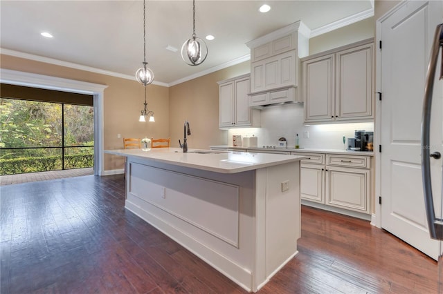 kitchen with a center island with sink, sink, dark hardwood / wood-style floors, tasteful backsplash, and decorative light fixtures