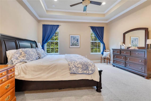 carpeted bedroom featuring a tray ceiling, multiple windows, and ceiling fan