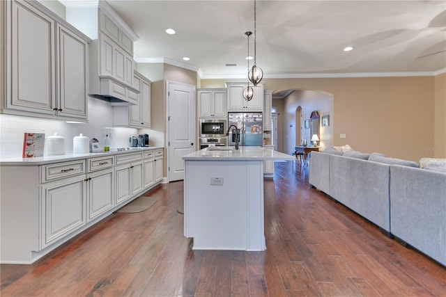 kitchen with backsplash, stainless steel fridge, decorative light fixtures, a kitchen island with sink, and a breakfast bar