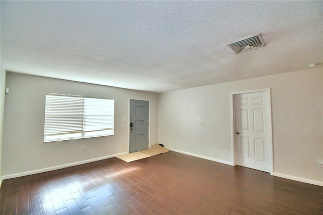 empty room featuring a textured ceiling and dark hardwood / wood-style floors