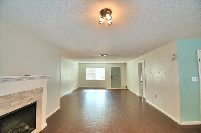 unfurnished living room featuring a fireplace, a textured ceiling, and dark hardwood / wood-style floors