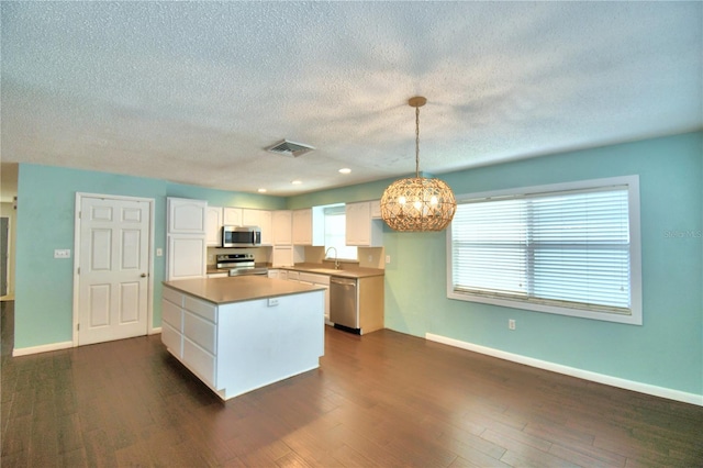 kitchen featuring stainless steel appliances, dark hardwood / wood-style flooring, white cabinetry, and pendant lighting