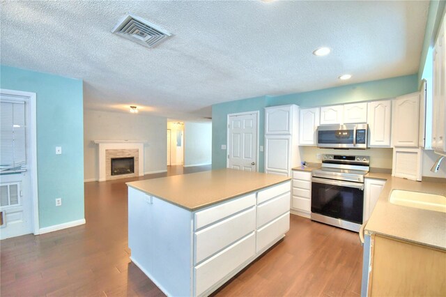 kitchen featuring sink, electric stove, hardwood / wood-style floors, and white cabinetry