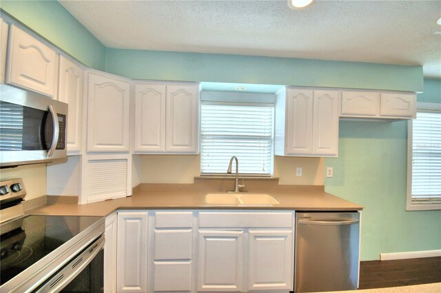 kitchen featuring appliances with stainless steel finishes, sink, a textured ceiling, and white cabinetry