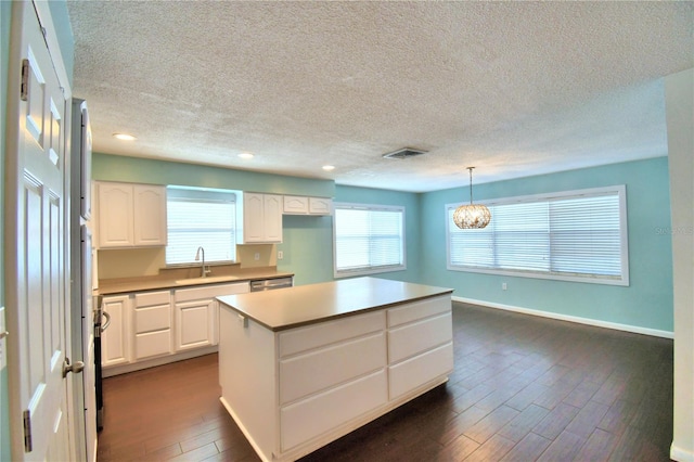 kitchen featuring dark hardwood / wood-style floors, a chandelier, white cabinets, hanging light fixtures, and a center island