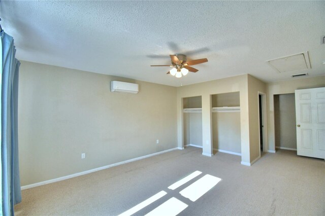 unfurnished bedroom with an AC wall unit, a textured ceiling, ceiling fan, and light carpet