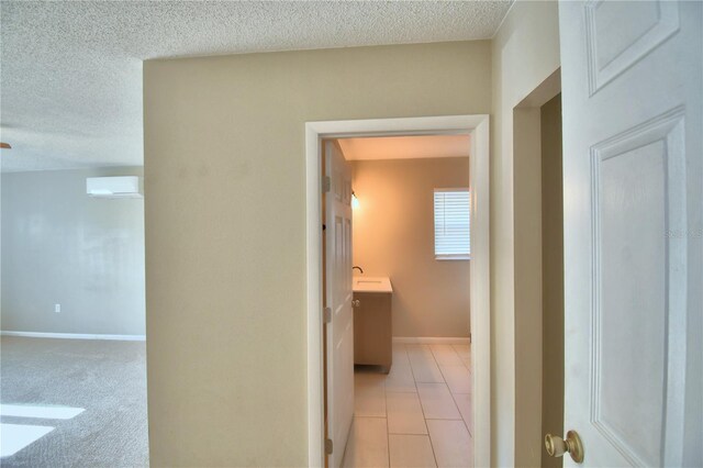 hallway featuring an AC wall unit, a textured ceiling, sink, and light colored carpet