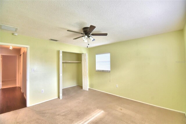 unfurnished bedroom featuring a textured ceiling, a closet, ceiling fan, and carpet floors