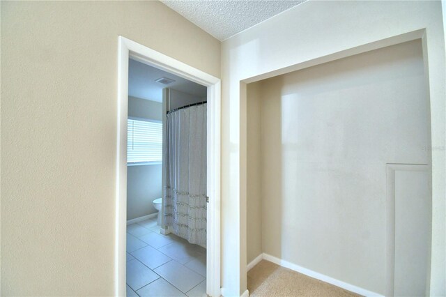 hall featuring a textured ceiling and light tile patterned floors