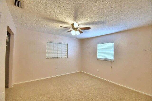 carpeted empty room with ceiling fan and a textured ceiling