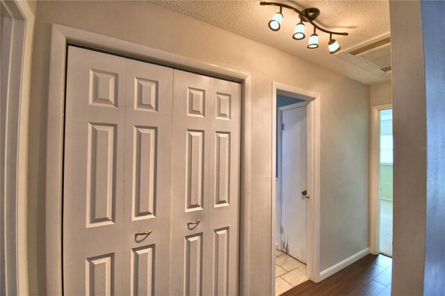 hall with a textured ceiling, tile patterned floors, and track lighting